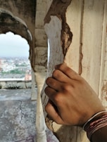 A hand gently tracing the carved patterns on a weathered wooden pillar, connecting past and present.