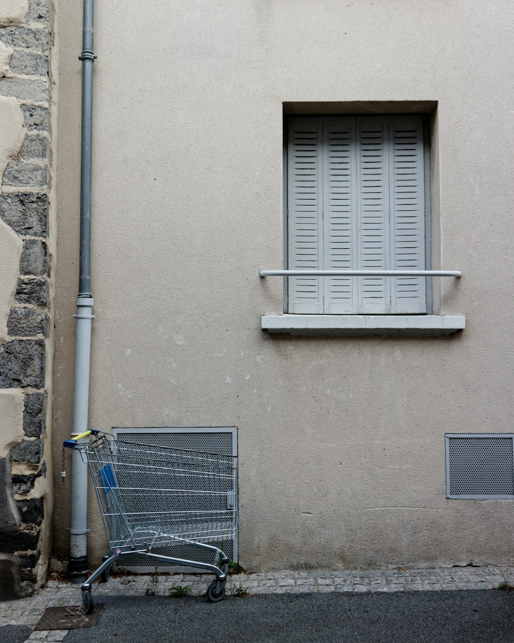 blue metal shopping cart beside gray concrete wall