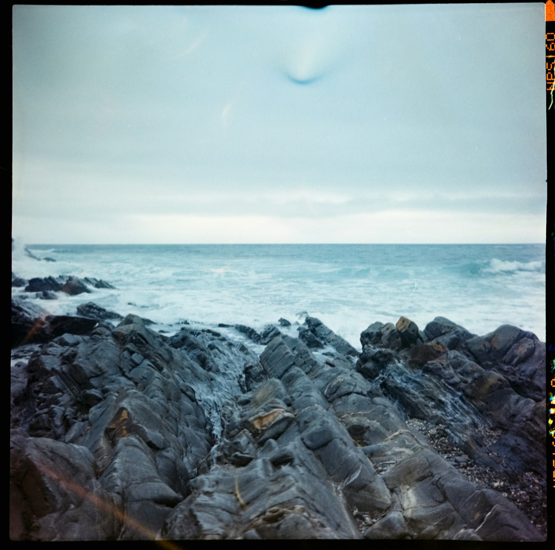 rocky shore with sea waves crashing on shore during daytime