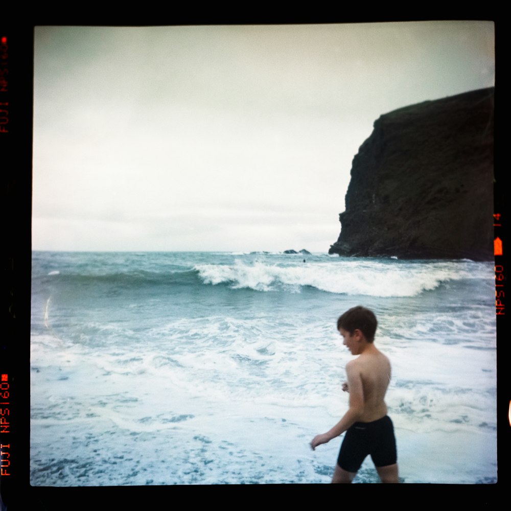 man in black shorts standing on seashore during daytime