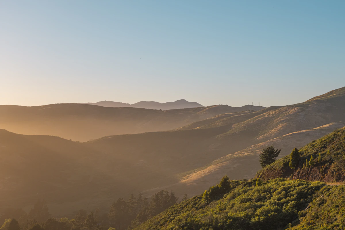 Low sun over the grassy ridges of the Marin Headlands, with a peak on the horizon