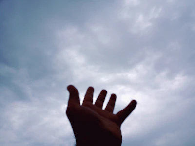 Hands reaching upward from darkness toward a radiant light breaking through clouds.