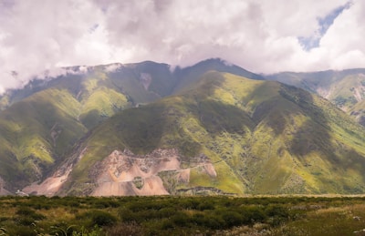 Rolling green mountains with morning sunlight breaking through the clouds.