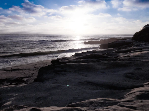 A serene shot of the rugged Atlantic coastline under soft morning light, waves gently lapping against weathered rocks.
