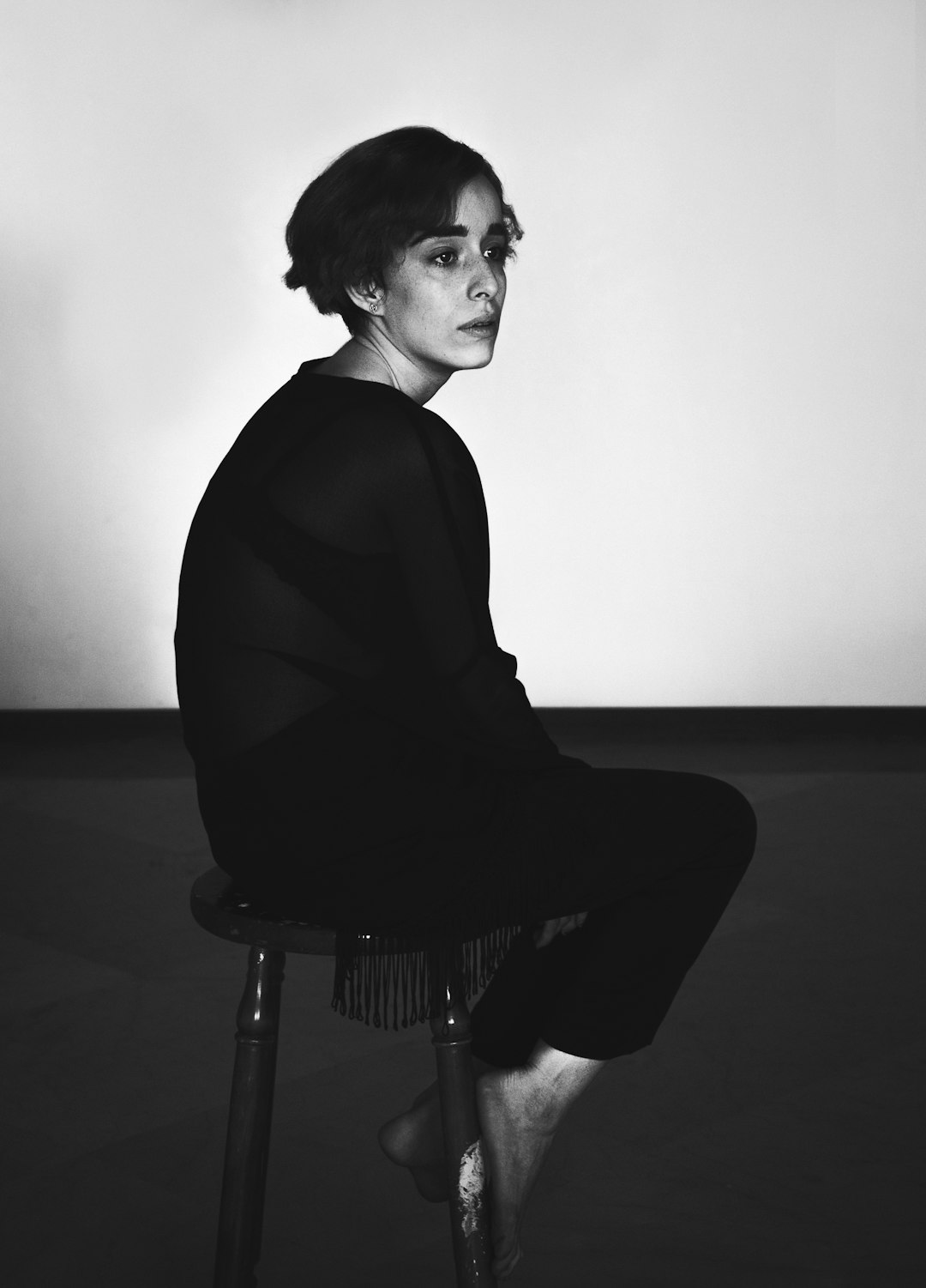 grayscale photo of woman in long sleeve shirt and pants sitting on chair