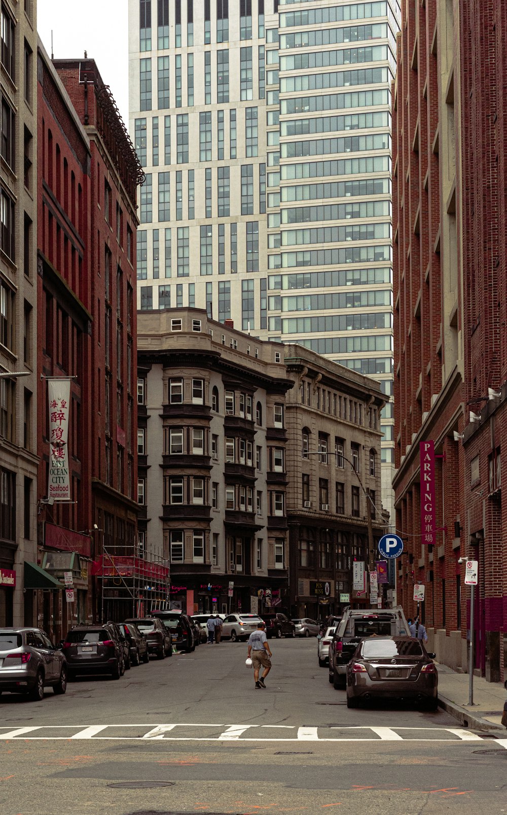 cars parked on street in between high rise buildings during daytime