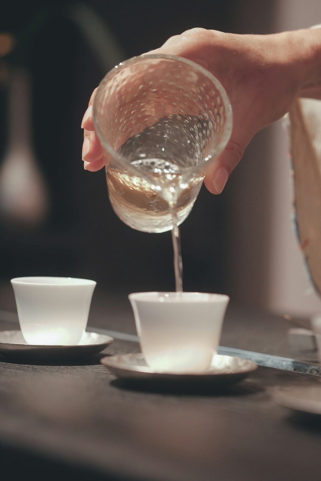 person pouring water on white ceramic cup