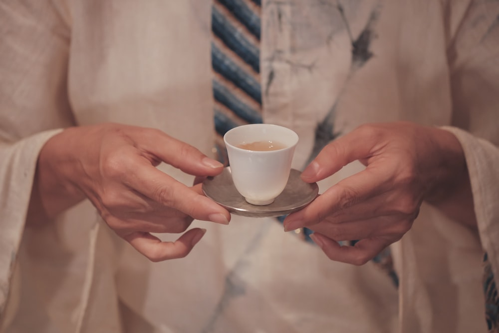 person holding white ceramic cup