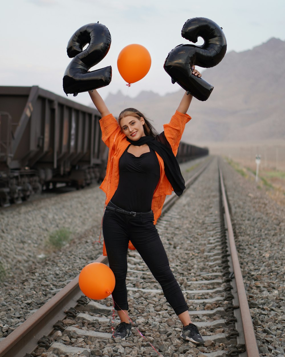 woman in black tank top and blue denim jeans holding orange ball