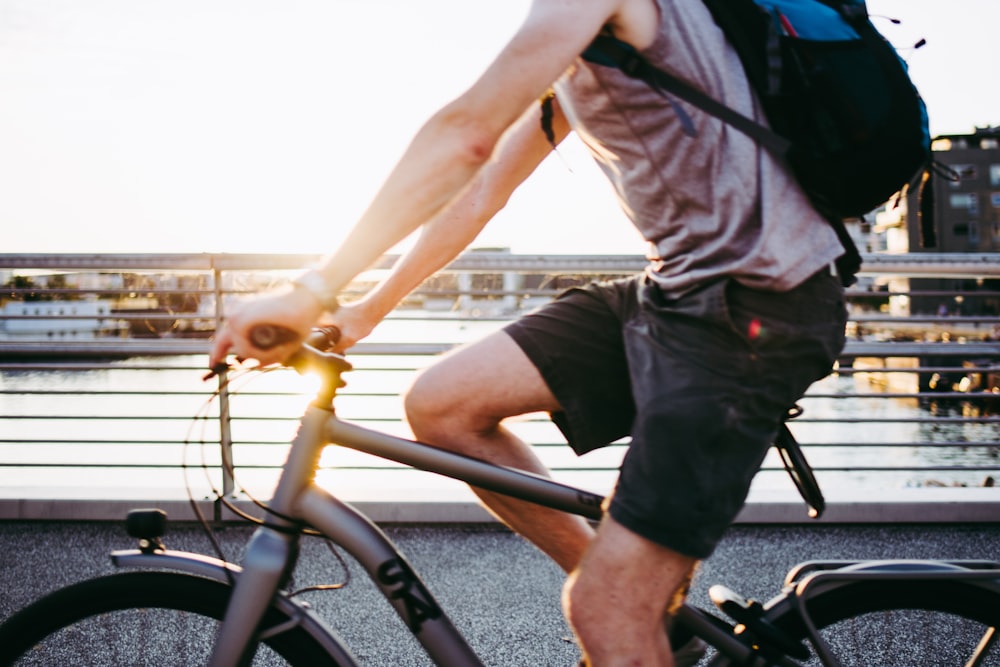 man in gray t-shirt and black shorts riding on bicycle during daytime