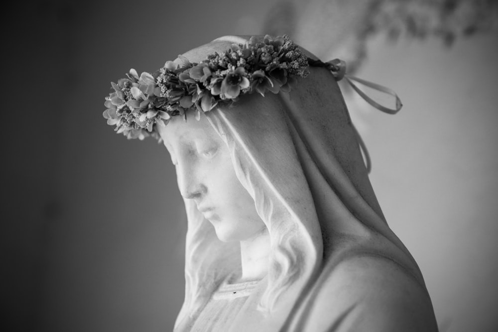 foto em tons de cinza da mulher com flor em sua estátua da cabeça