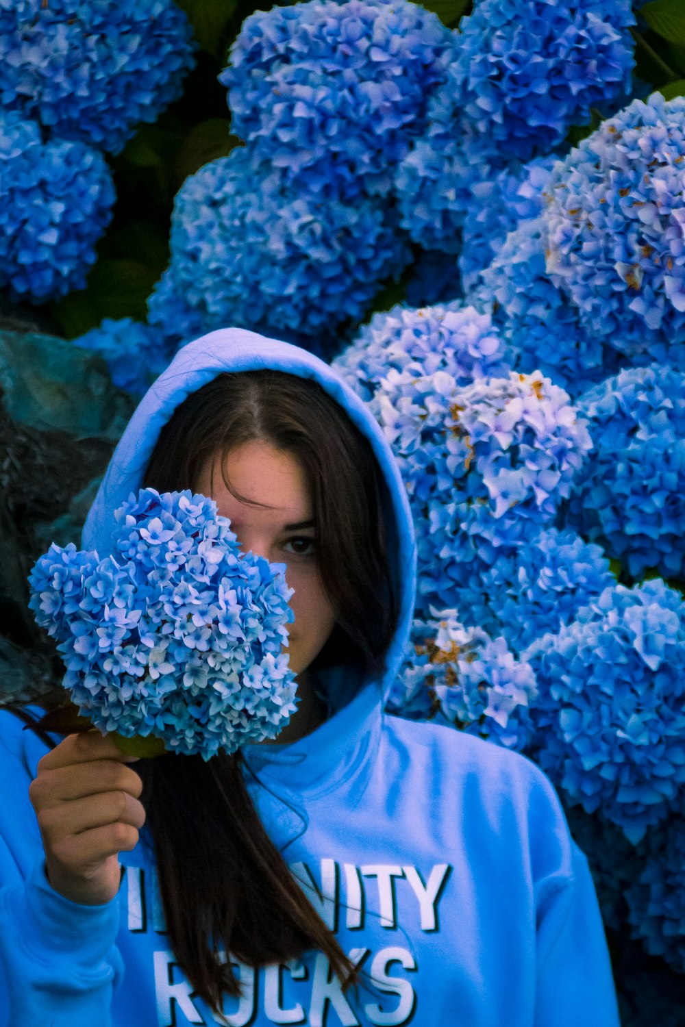 woman in blue hijab holding blue flowers