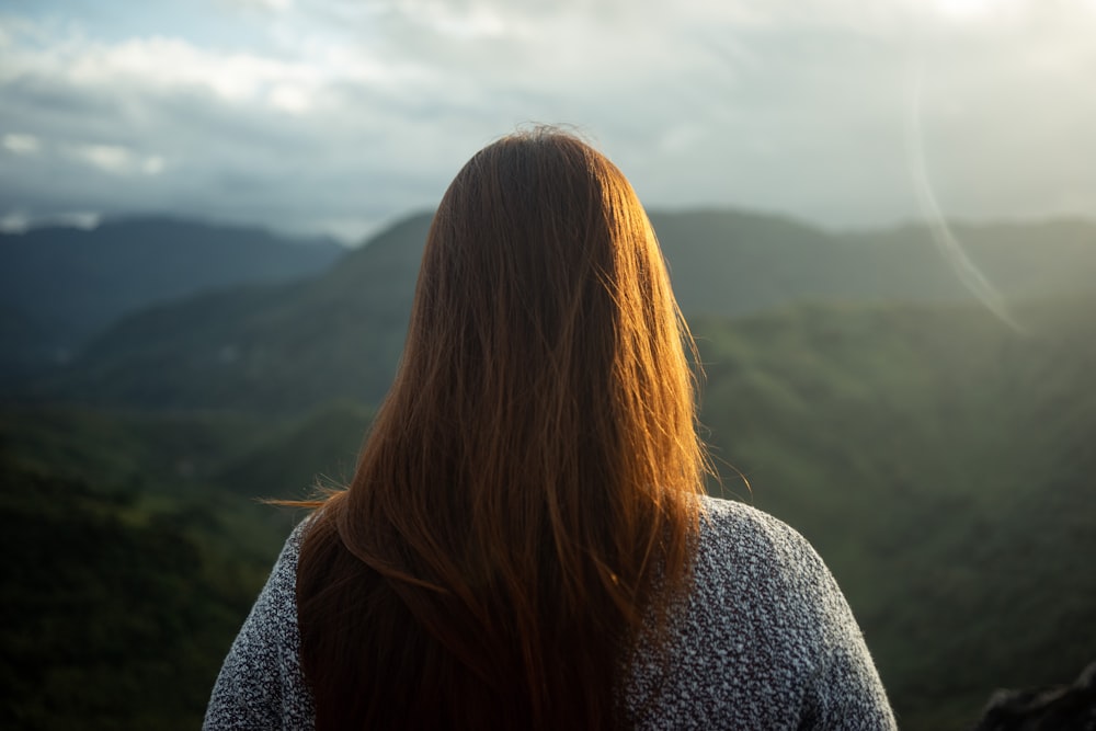 woman in gray knit sweater standing on mountain during daytime