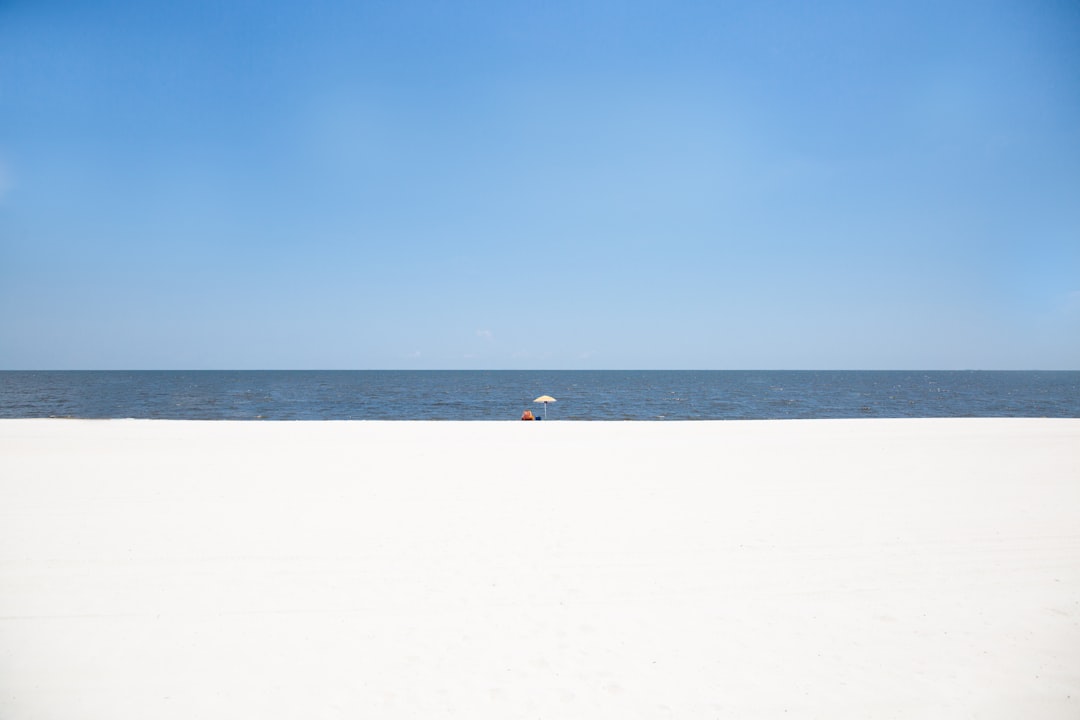 person walking on white sand beach during daytime