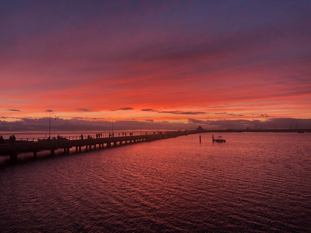 silhouette of bridge over body of water during sunset