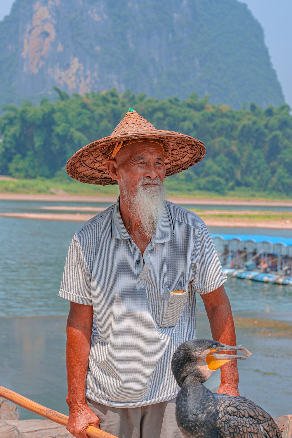 man in white button up shirt wearing brown straw hat standing near body of water during