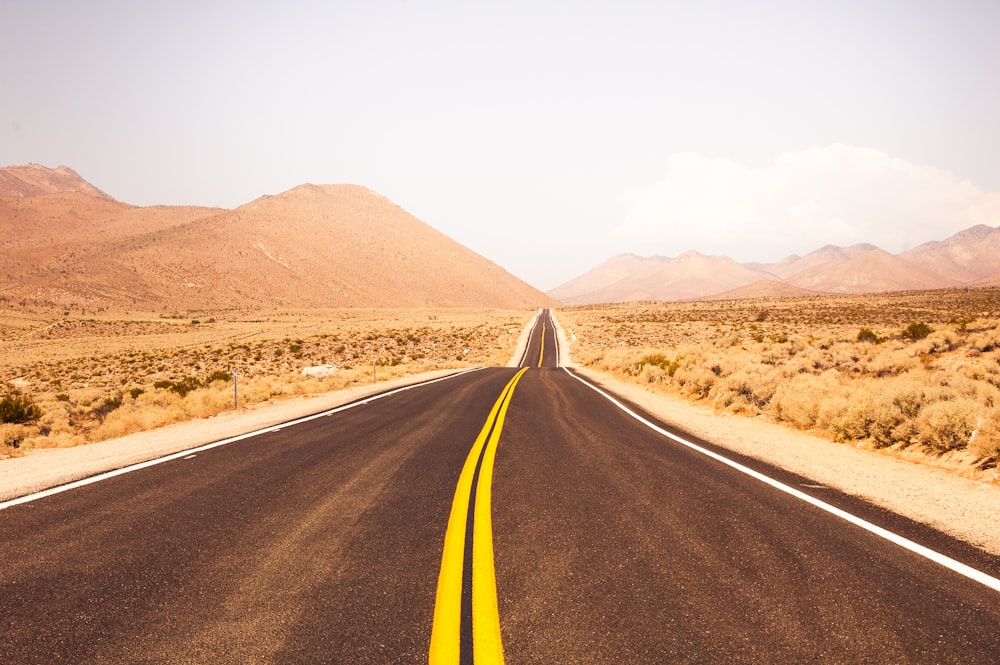 Carretera de asfalto negro en medio de Brown Field durante el día