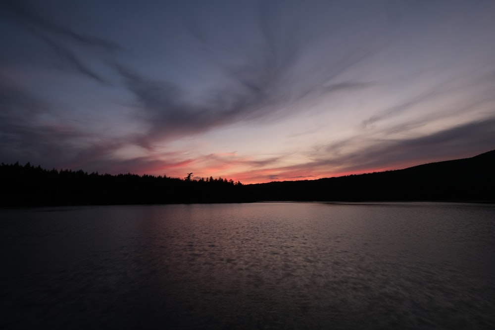 a sunset over a lake with trees in the background