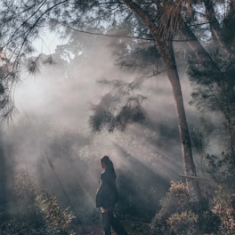 A serene outdoor scene of a woman in her 40s walking through a sunlit forest path, embodying calm and vitality.