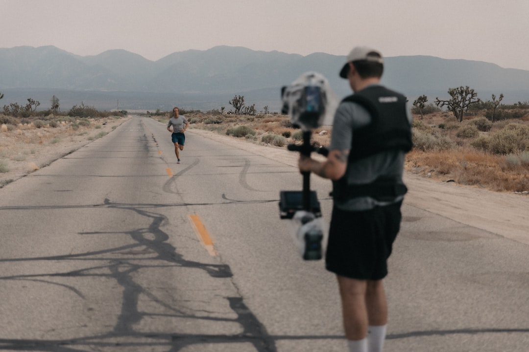 man in black jacket and black shorts walking on gray concrete road during daytime