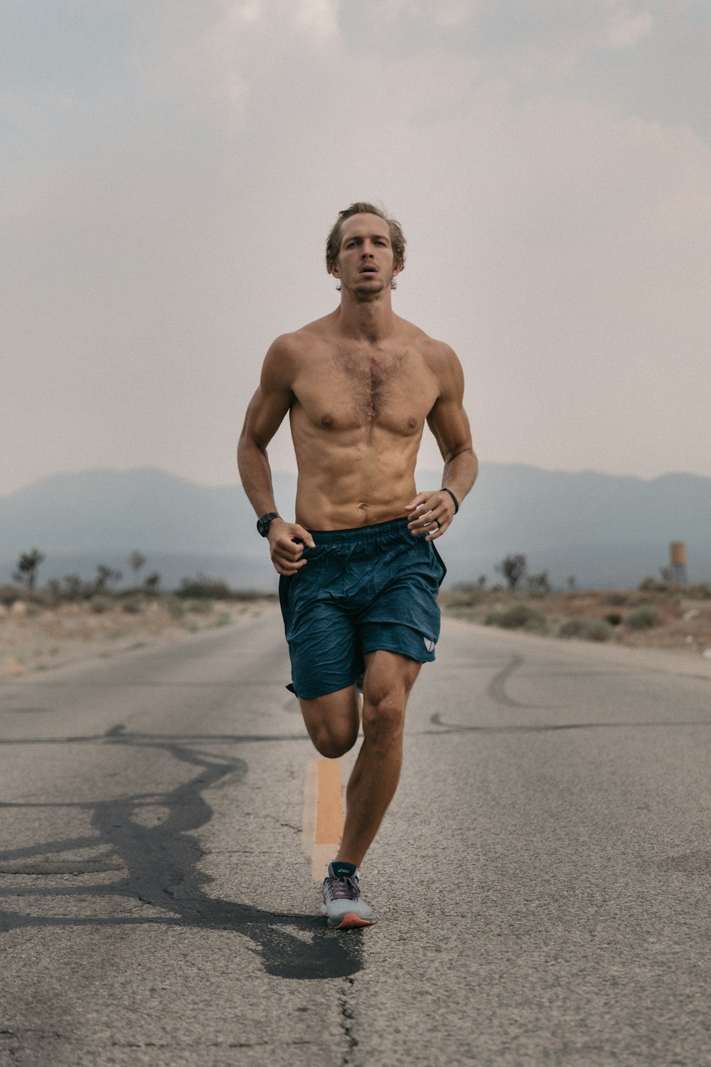 a shirtless man running down a road