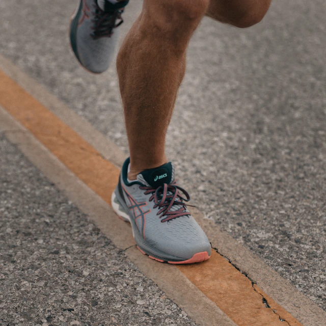 A person running in gray ASICS sneakers