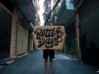 person standing on sidewalk with better days sign