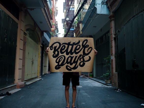 person standing on sidewalk with better days sign