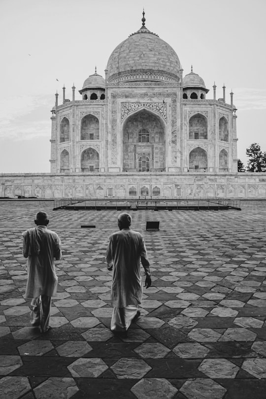grayscale photo of man walking on sidewalk in Taj Mahal India