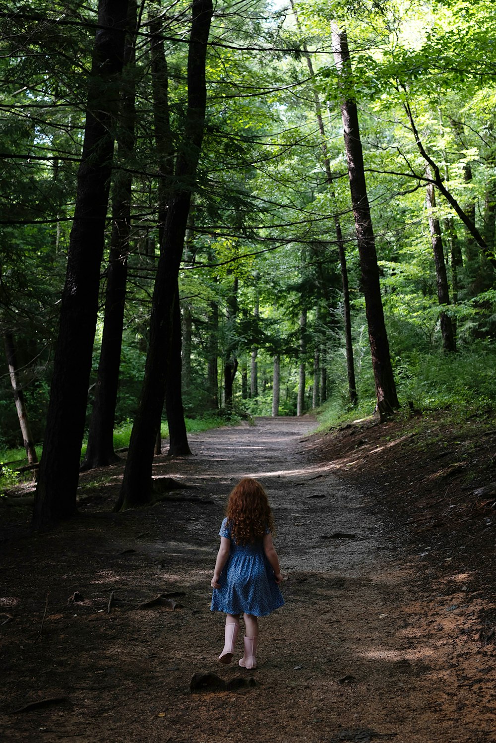 woman in blue denim jacket walking on forest during daytime