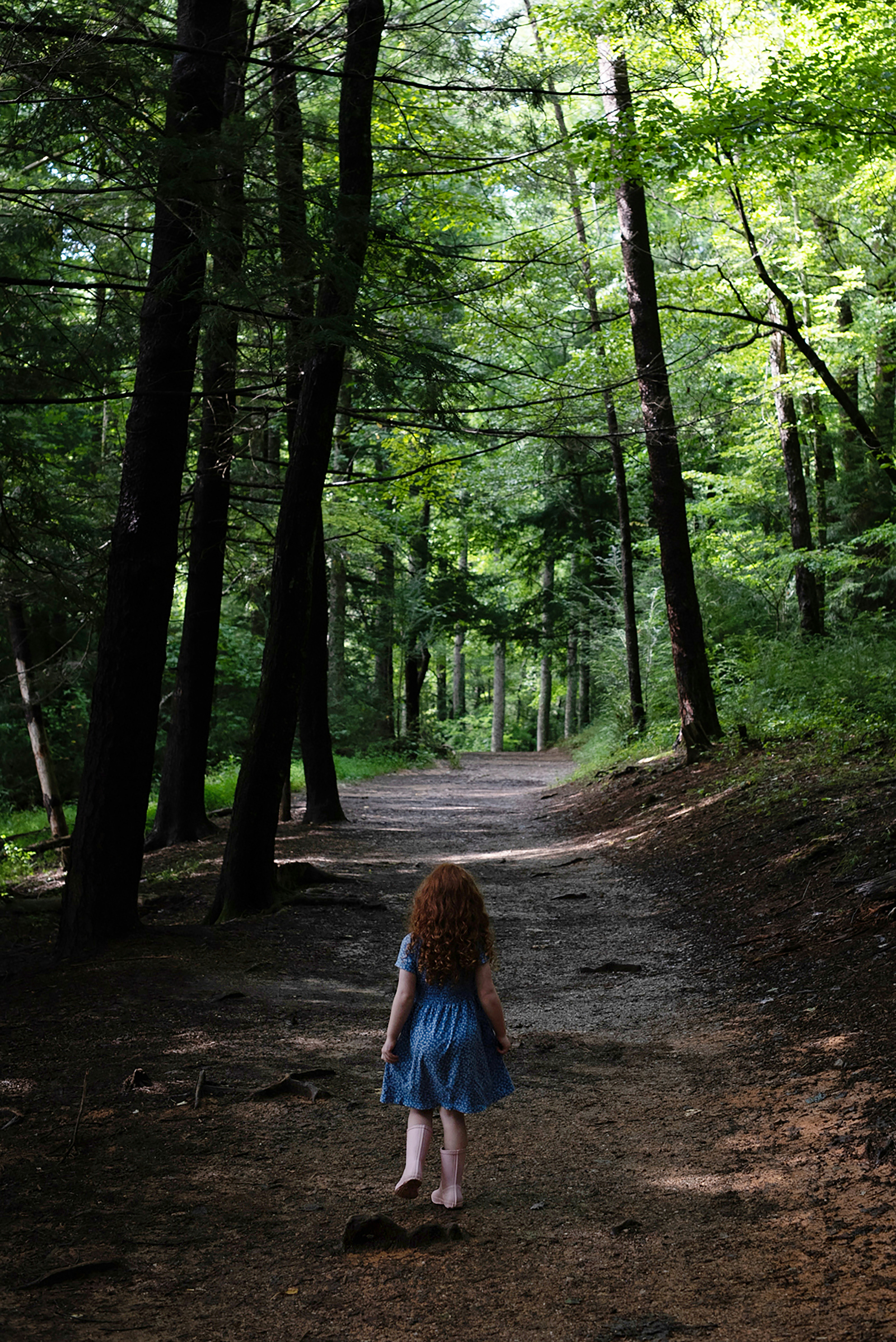woman in blue denim jacket walking on forest during daytime