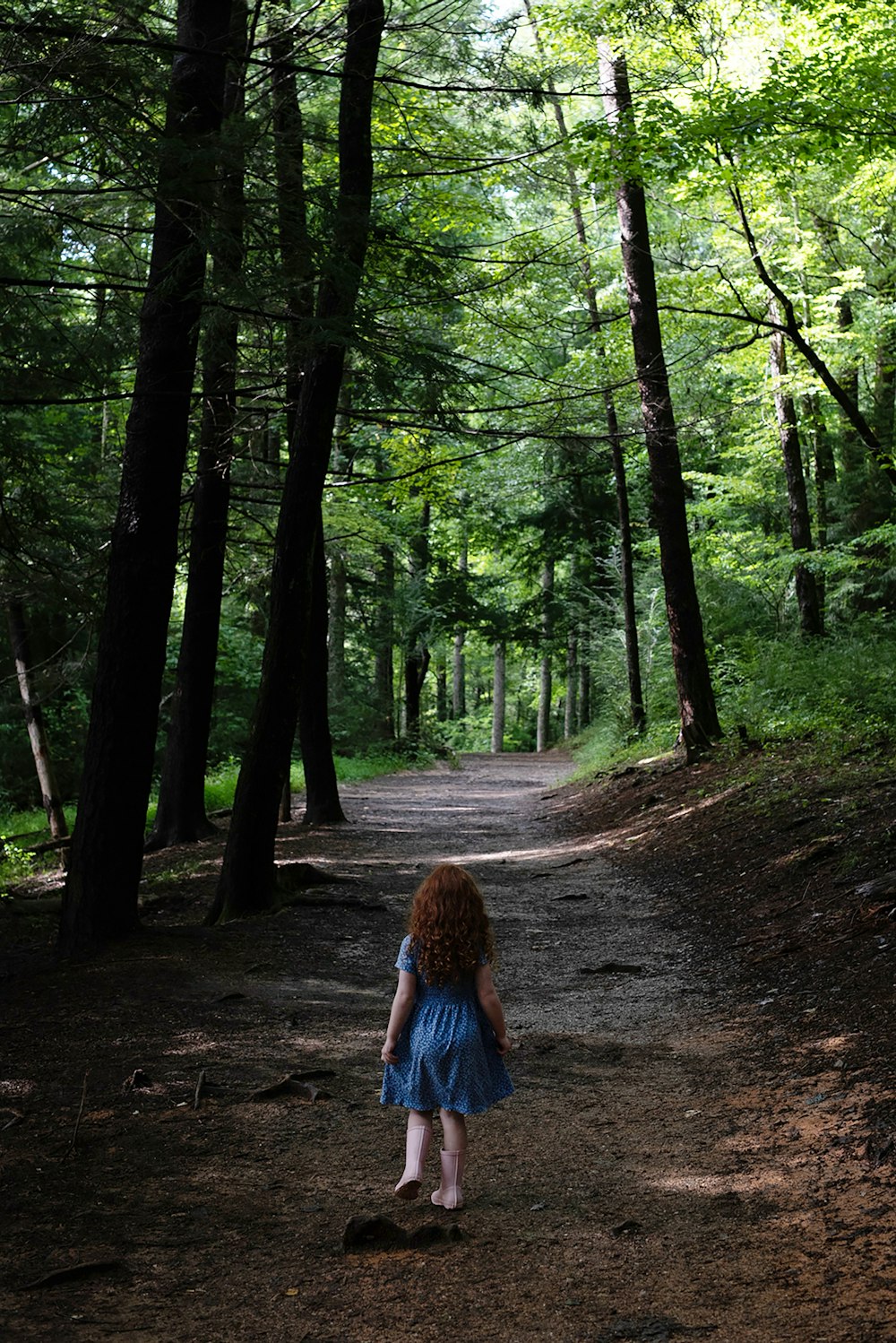 昼間の森を歩くブルーデニムジャケットの女性