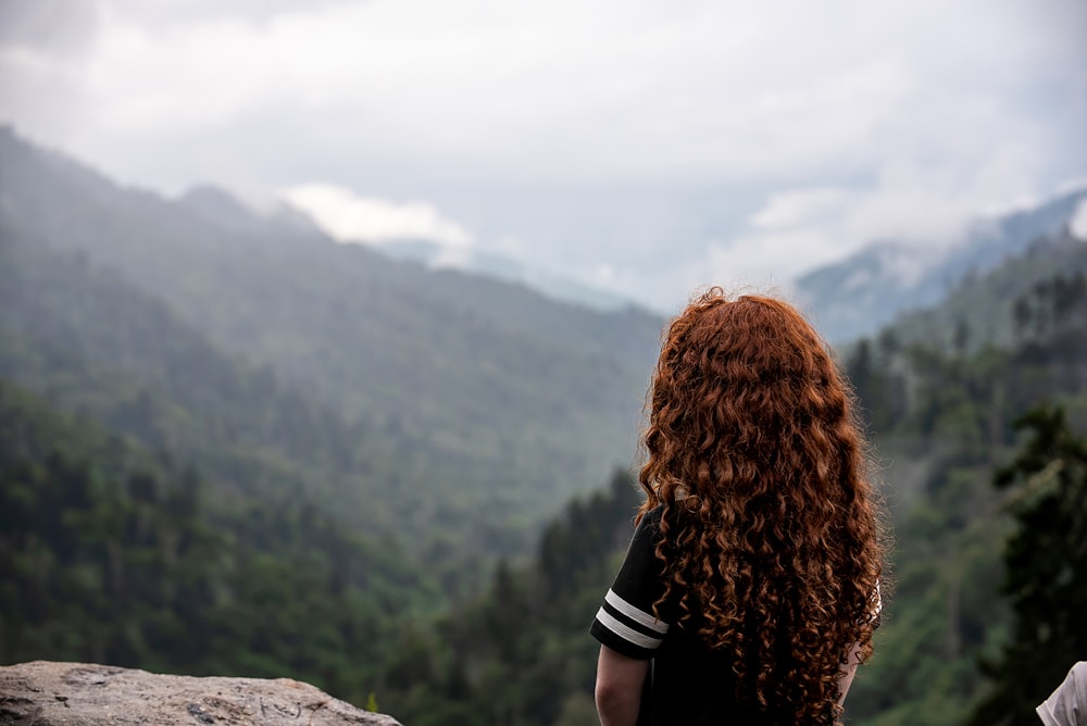 woman in black shirt standing on rock during daytime