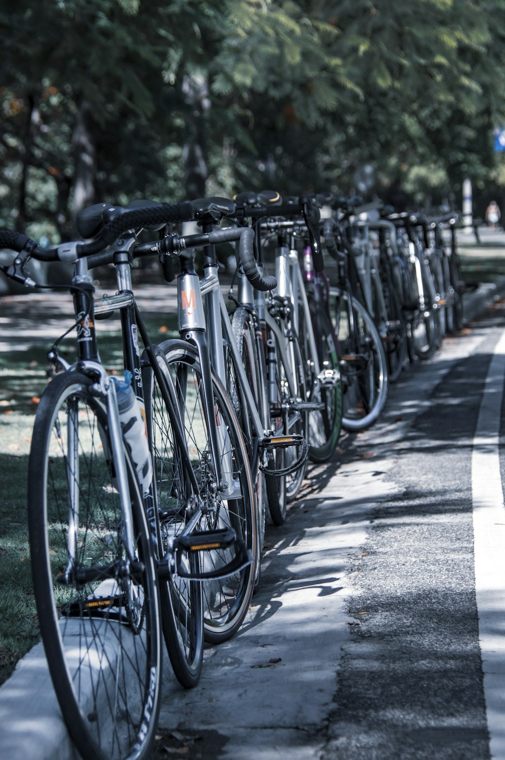 blue and black road bikes parked on gray concrete road during daytime