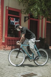 man in black t-shirt riding on teal bicycle during daytime