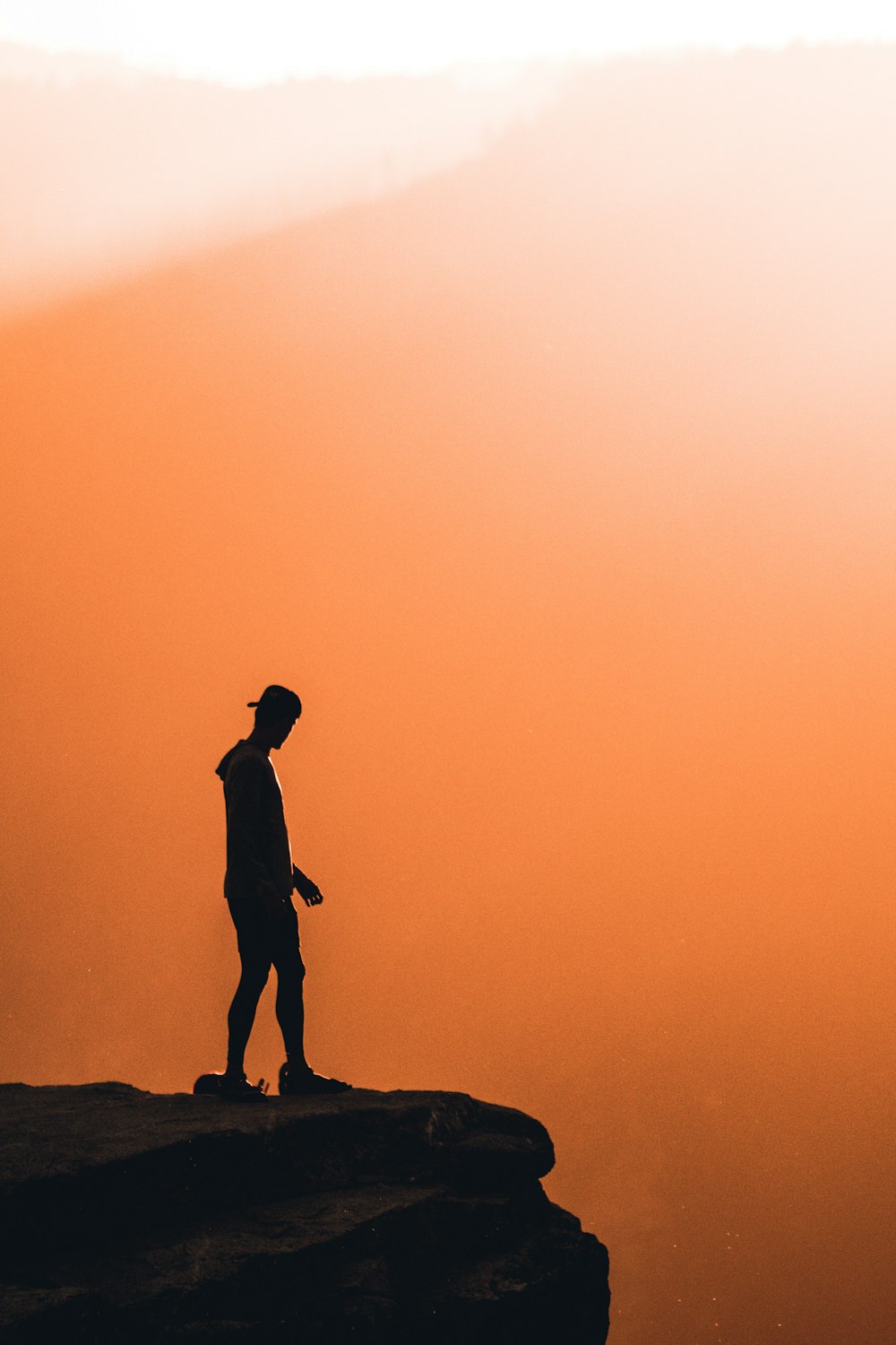 silhouette of man standing on rock during sunset