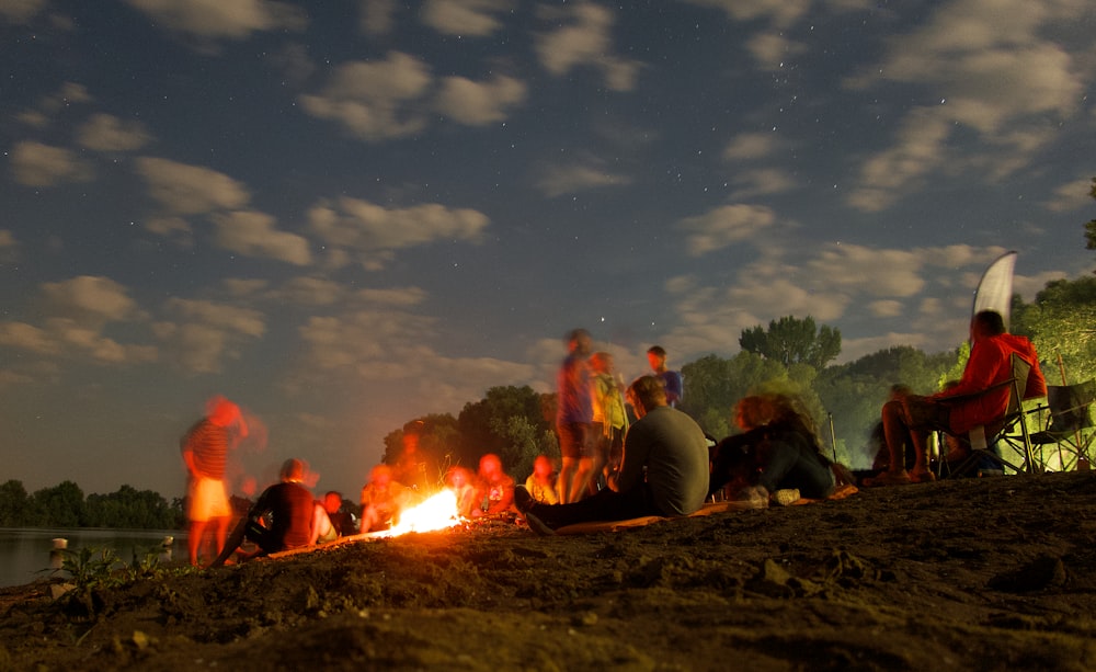 people sitting on ground near bonfire during night time