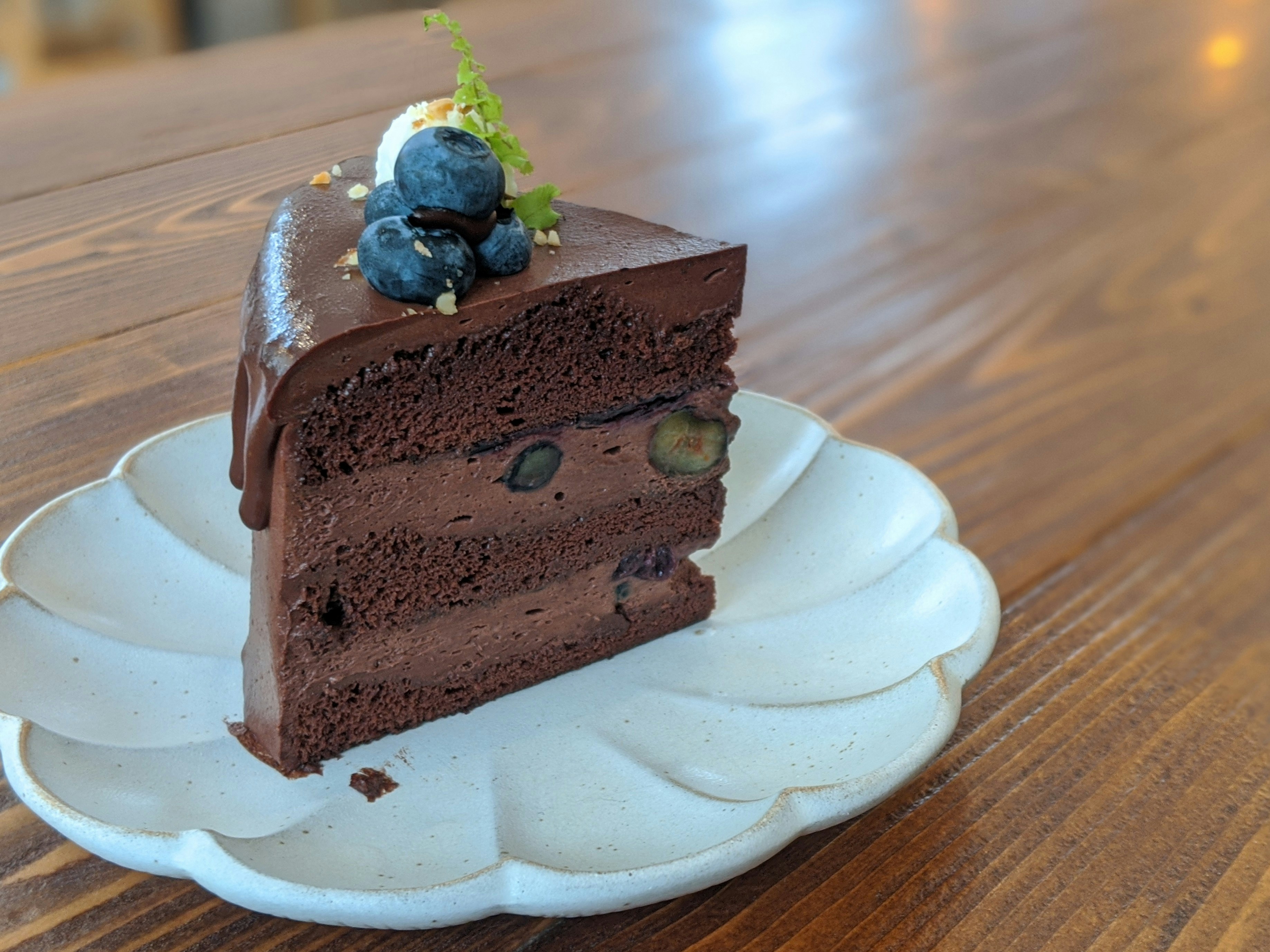 Stunning premium cake slice with multiple layers of chocolate sponge and cream frosting on dark slate surface, professional food photography