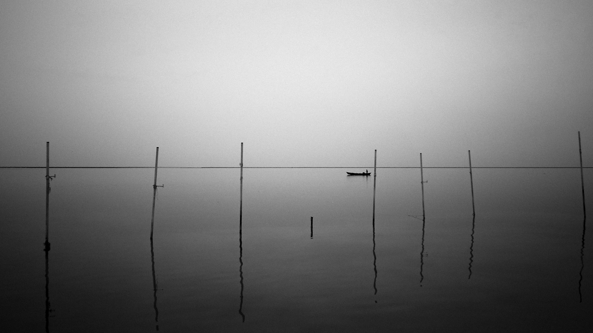 grayscale photo of 2 poles on body of water