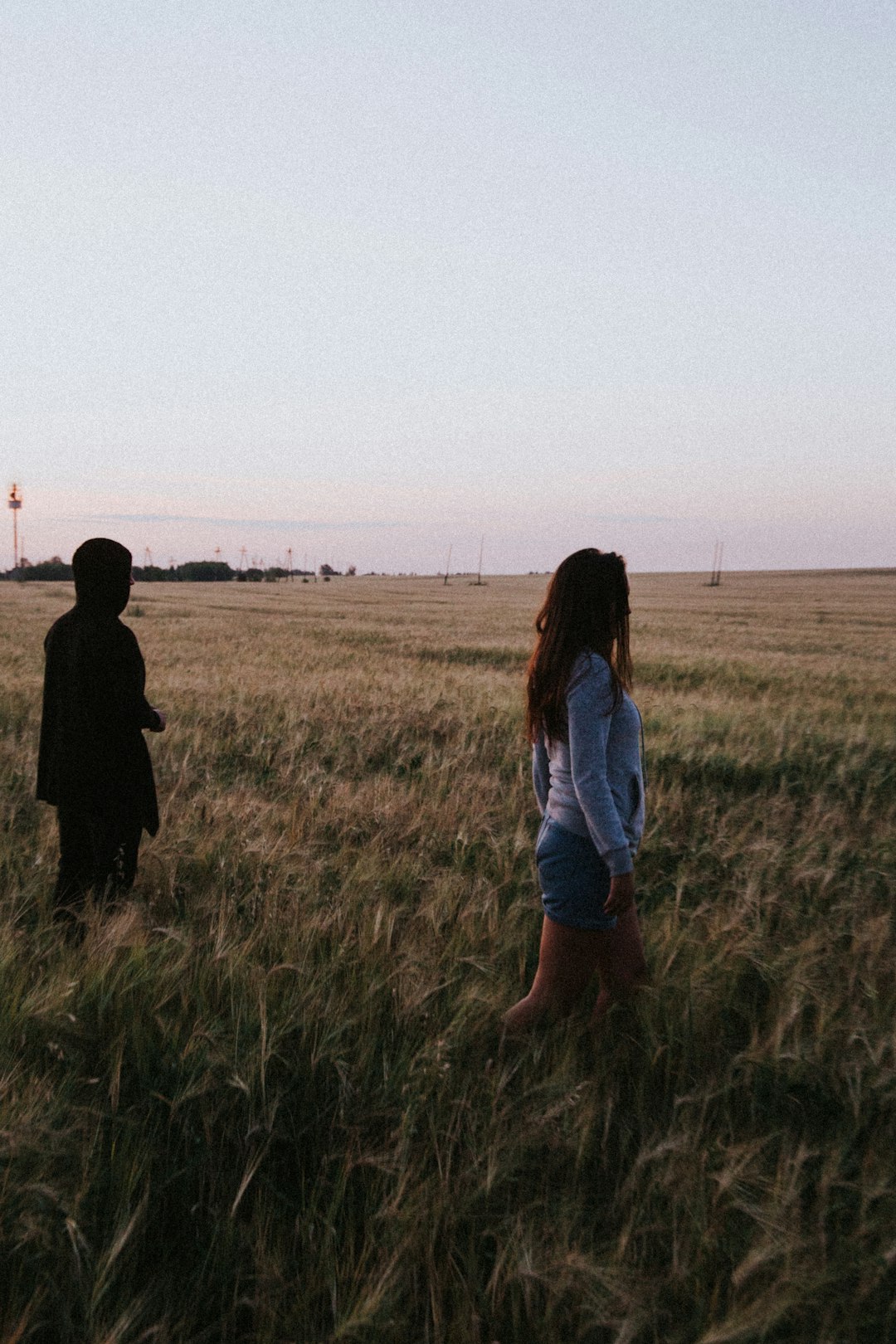 woman in white shirt and blue denim shorts standing on green grass field during daytime