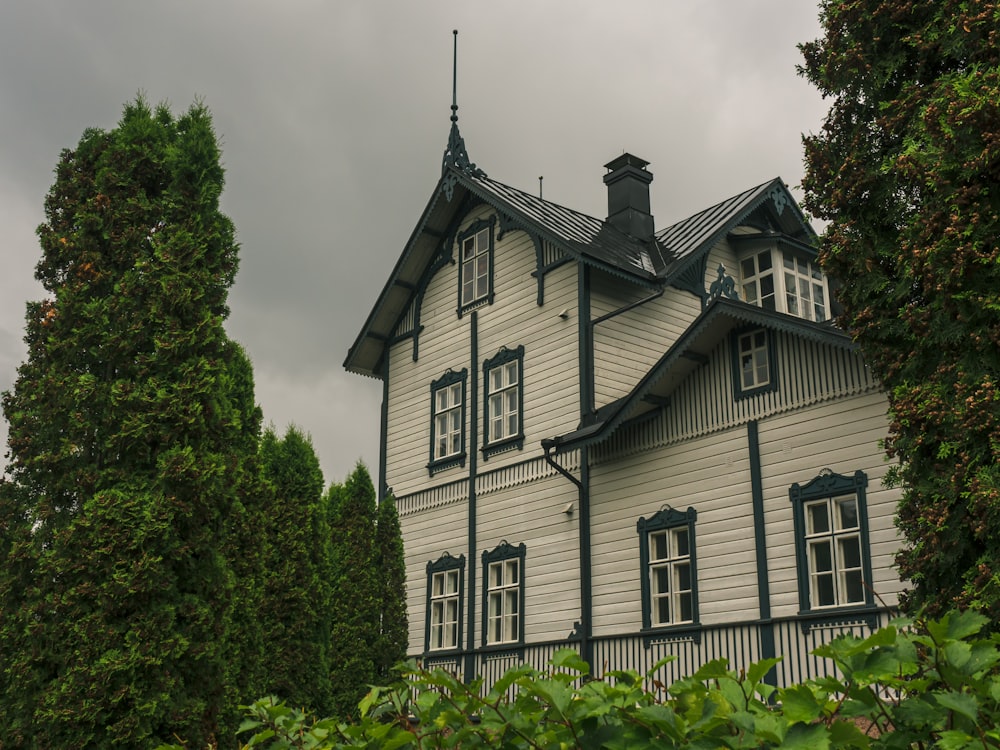 white and black house near green trees under white clouds during daytime