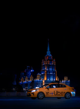 An Uber car glowing under streetlights with illuminated ads on its windows during nighttime.