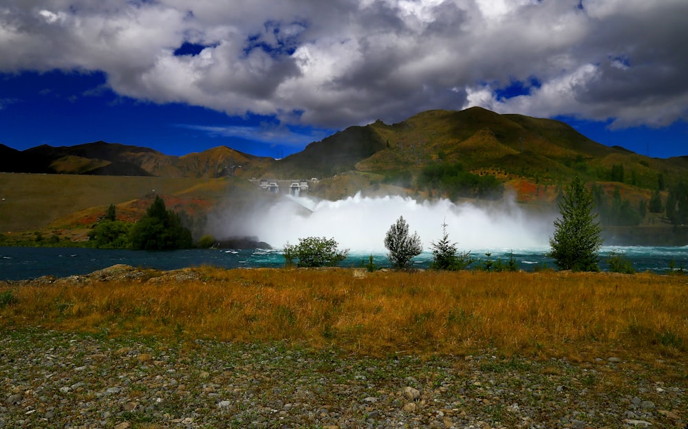 green grass field near mountain under white clouds during daytime