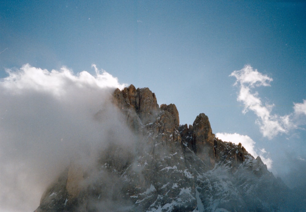 brown rocky mountain covered with white clouds during daytime