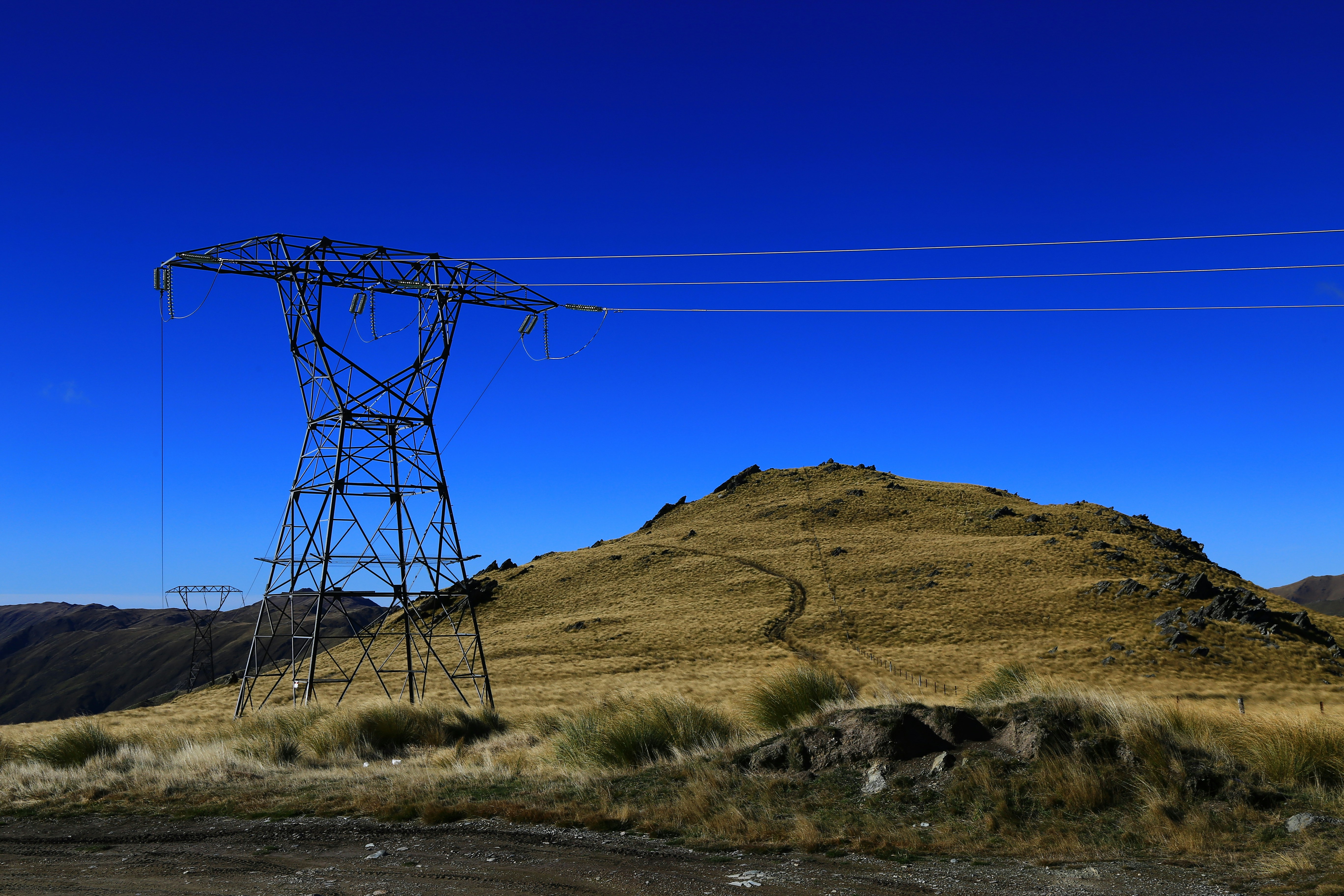 black electric post on green grass field under blue sky during daytime