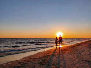 Couple walking hand in hand along a quiet Atlantic beach at sunset