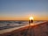 A loving couple walking hand-in-hand along a picturesque beach at sunset.