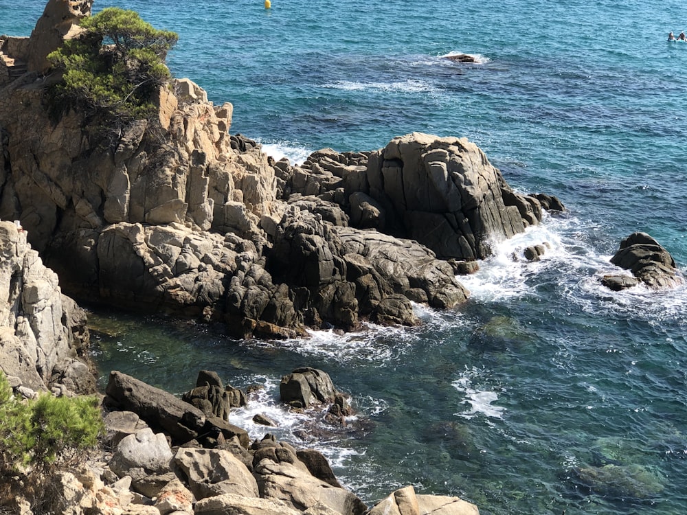 brown rocky mountain beside body of water during daytime