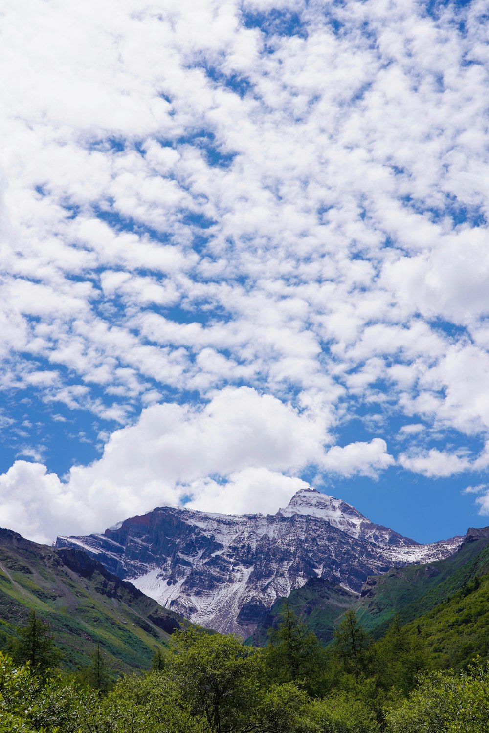 green and white mountains under white clouds and blue sky during daytime