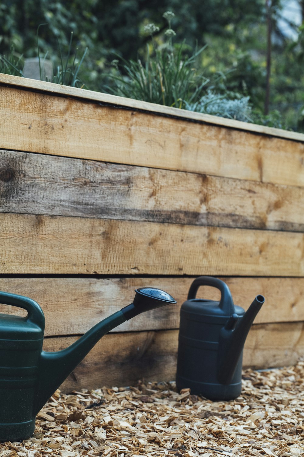 green plastic watering can beside brown wooden wall